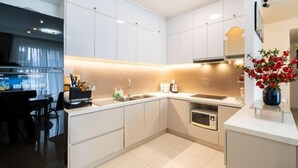 A modern kitchen with white cabinets, a countertop, and a sink. - Gin House - Golden Mansion Apartment Phu Nhuan District (Ho Chi Minh City)