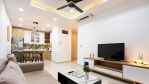 A modern living room with a sofa, a coffee table, a TV, and a ceiling fan. - Gin House - Golden Mansion Apartment Phu Nhuan District (Ho Chi Minh City)