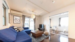 A modern living room with a blue sofa, a coffee table, and a television. - Iris Tokyo ２ (Tokyo)