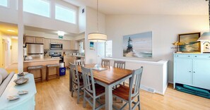 A spacious kitchen with modern appliances, a dining area with wooden chairs, and a view of the sea through a window.