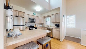 Una cocina moderna con una isla central, electrodomésticos de acero inoxidable y armarios de madera clara.