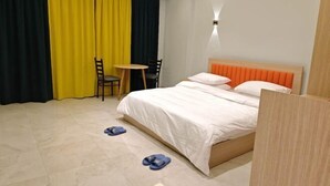 Una habitación de hotel con cama, una mesita, dos sillas y un escritorio.