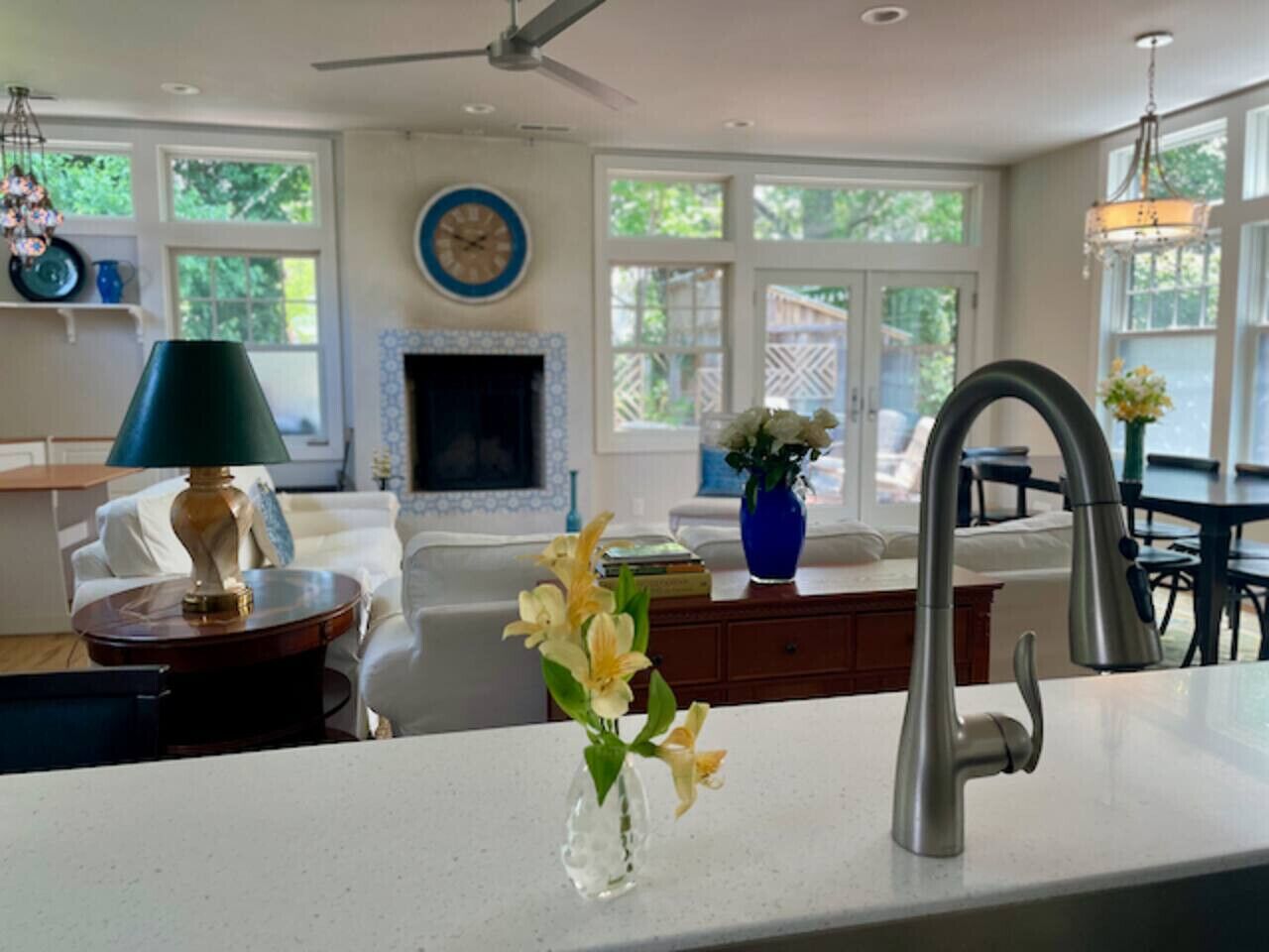 A kitchen with a modern faucet, a vase with flowers, and a dining area with a chandelier.