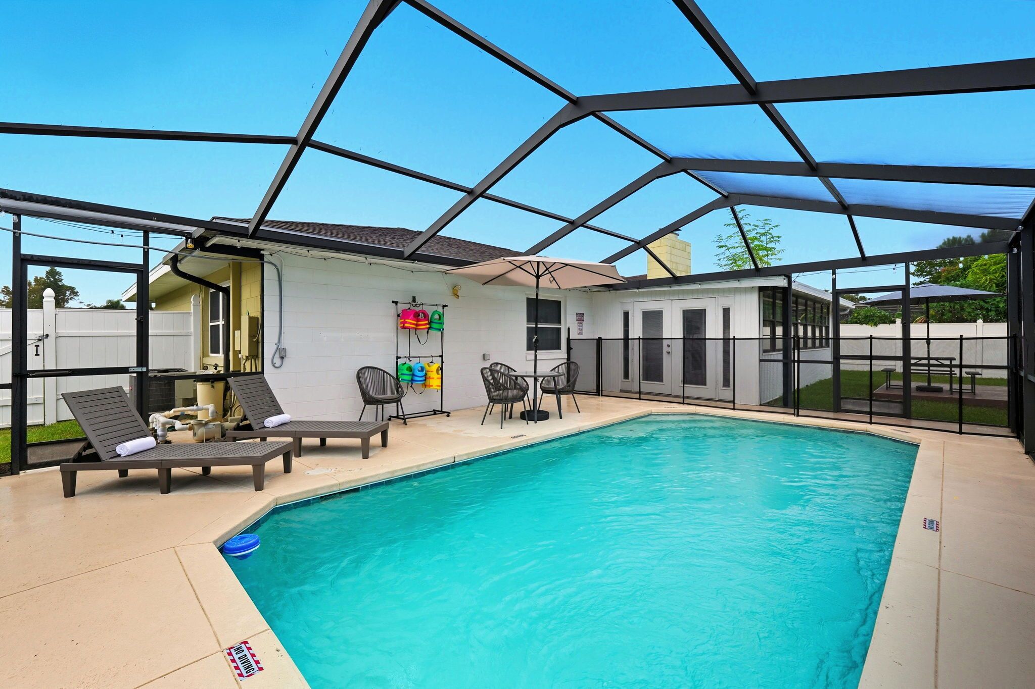 Une piscine avec des chaises longues et un espace patio couvert.