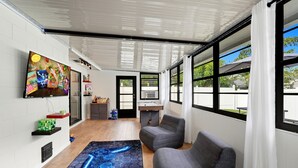 Un salon moderne doté d’un téléviseur à écran plat, de sièges confortables, d’un bureau et de grandes fenêtres.