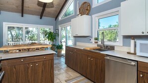 Una cocina moderna con armarios de madera, una isla central y ventanas amplias.