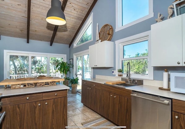 A modern kitchen with wooden cabinets, a central island, and large windows. - WOW! THE ULTIMATE LUXURY BEACH HOME PRIVATE GULF FRONT BEACH AND LEMON BAY TOO!  (Englewood)