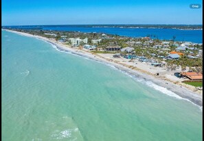 Eine Vogelperspektive eines Küstenresorts mit Strandhäusern, klarem, blauem Wasser und einem Blick auf den Ozean in der Ferne.