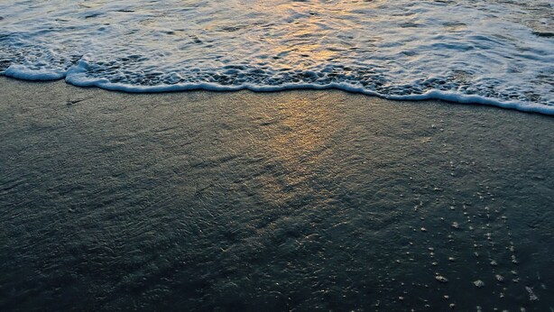 Una playa con olas y un atardecer.