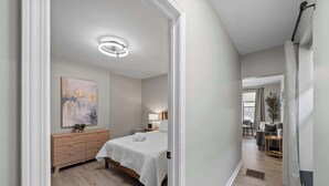 A modern bedroom with a bed, bedside table, lamp, and artwork on the wall. - The Luxe Pearl Residences 8ppl (Columbus)