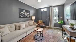 A living room with a sofa, a round coffee table, a lamp, a chair, a floor lamp, and a window with curtains. - The Luxe Pearl Residences 8ppl (Columbus)