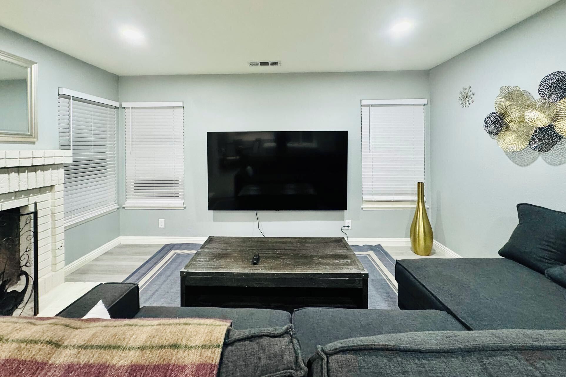 A living room with a flat-screen TV mounted on the wall, a fireplace, and a sofa.