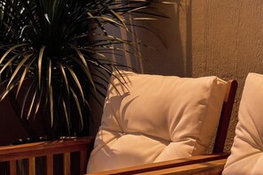 Een comfortabele stoel met een houten frame, geplaatst naast een potplant.