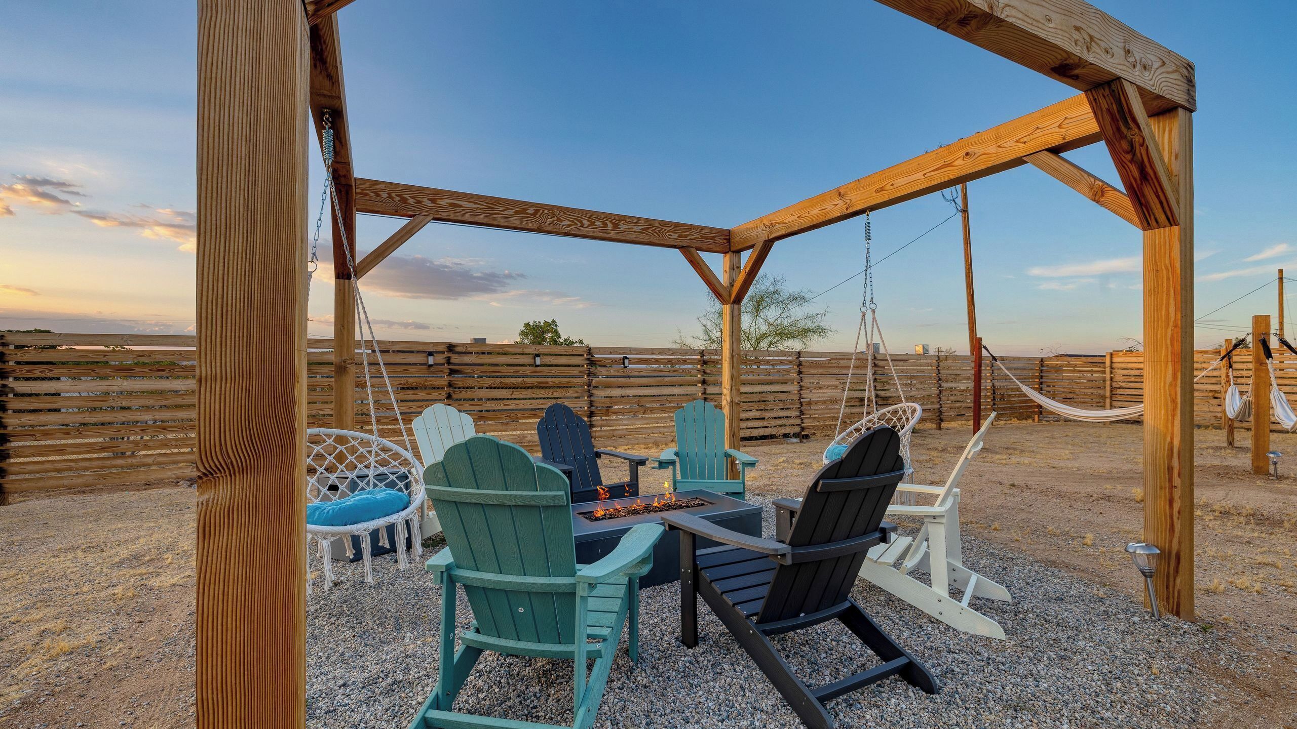 A wooden pergola with a fire pit and seating area.