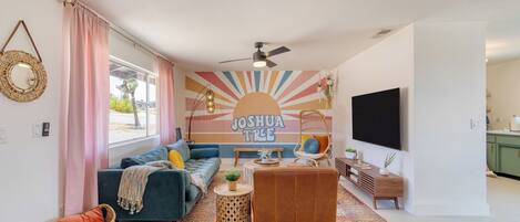 A modern living room with a sofa, a coffee table, a TV, and a wall mural.