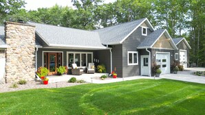 A modern two-story house with a stone facade, a covered porch, and a well-maintained lawn.