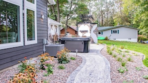 A residential property with a patio, outdoor seating, a hot tub, and a garden with various plants and flowers.
