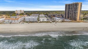 Un hotel frente al mar con varias construcciones, una playa y vistas al océano.