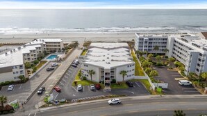 Un hotel frente a la playa con varias edificaciones, un estacionamiento y vistas al océano.