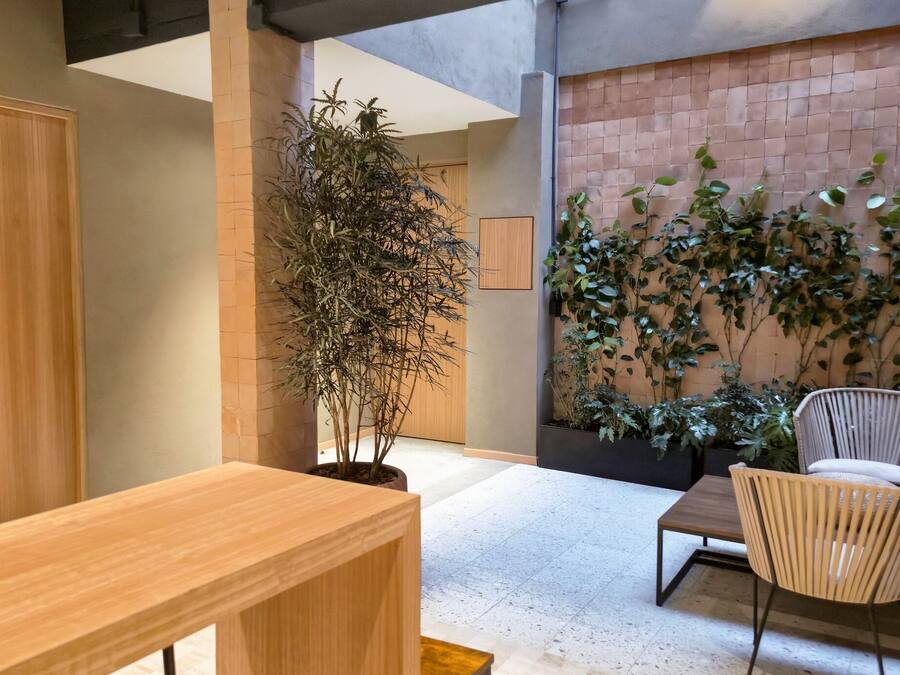 A modern interior with a wooden door, a potted plant, a brick wall, and a seating area with a chair and table.