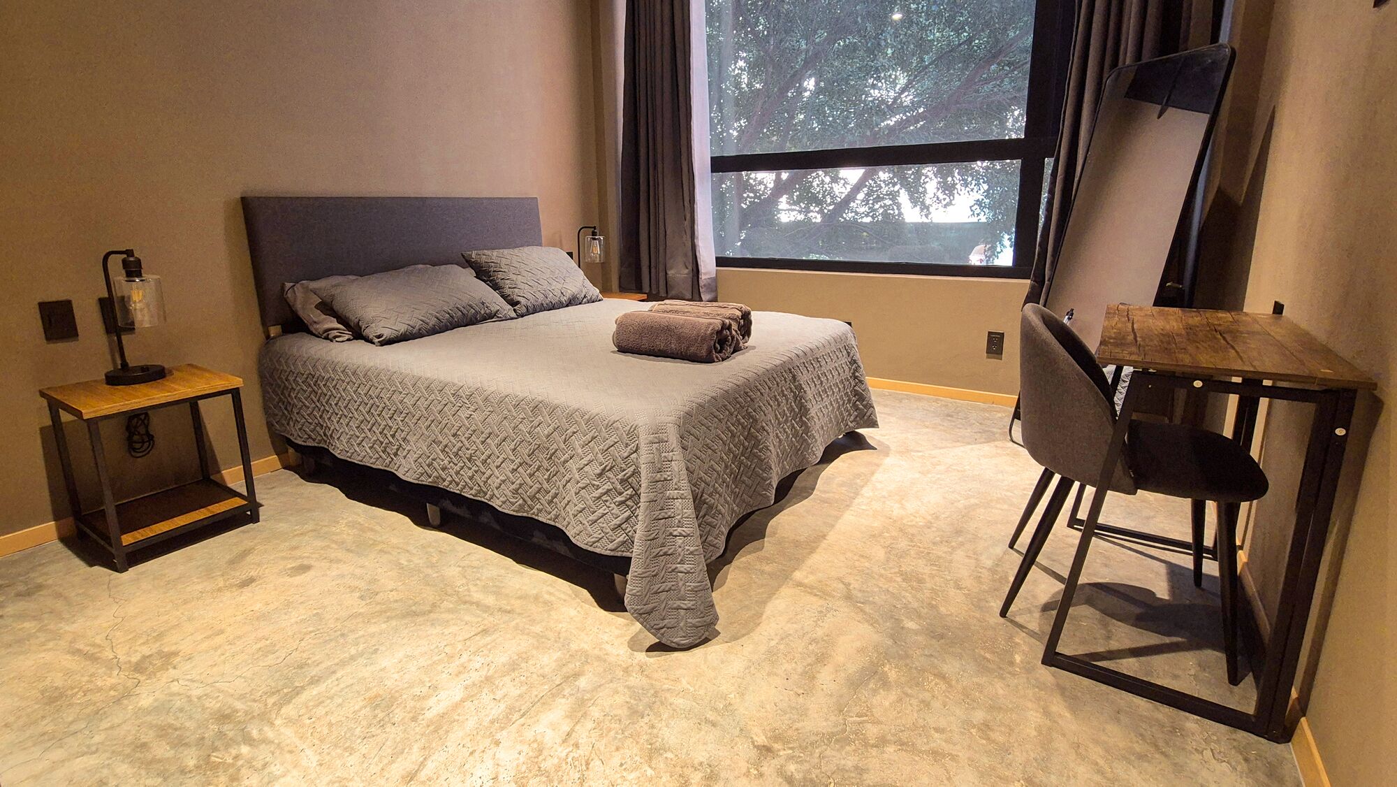 A bedroom with a bed, a desk, and a chair.