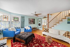 A living room with a blue sofa, a white sofa, a red patterned rug, and a wooden staircase. - Unique & Walkable 3-BR - 2 Offices & Fenced Yard (Charlottesville)