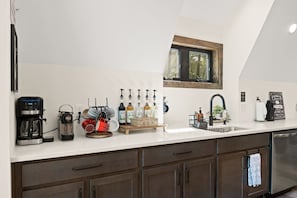 Una cocina moderna con encimera blanca, electrodomésticos de acero inoxidable y una ventana sobre el fregadero.
