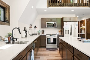 Una cocina moderna con una isla grande, electrodomésticos de acero inoxidable y muebles de madera.