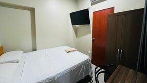 Habitación de hotel con una cama, un armario, un televisor de pantalla plana en la pared y un equipo de aire acondicionado.