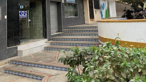 Un hotel llamado "HOTEL TUMPI" con una fachada moderna, una escalera que conduce a la entrada y un pequeño jardín al frente.