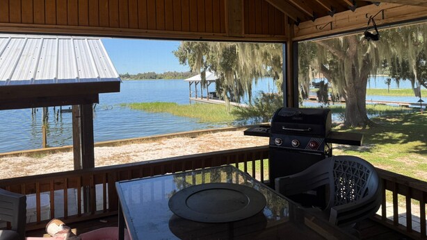 Überdachter Außenbereich mit Grill und Seeblick.