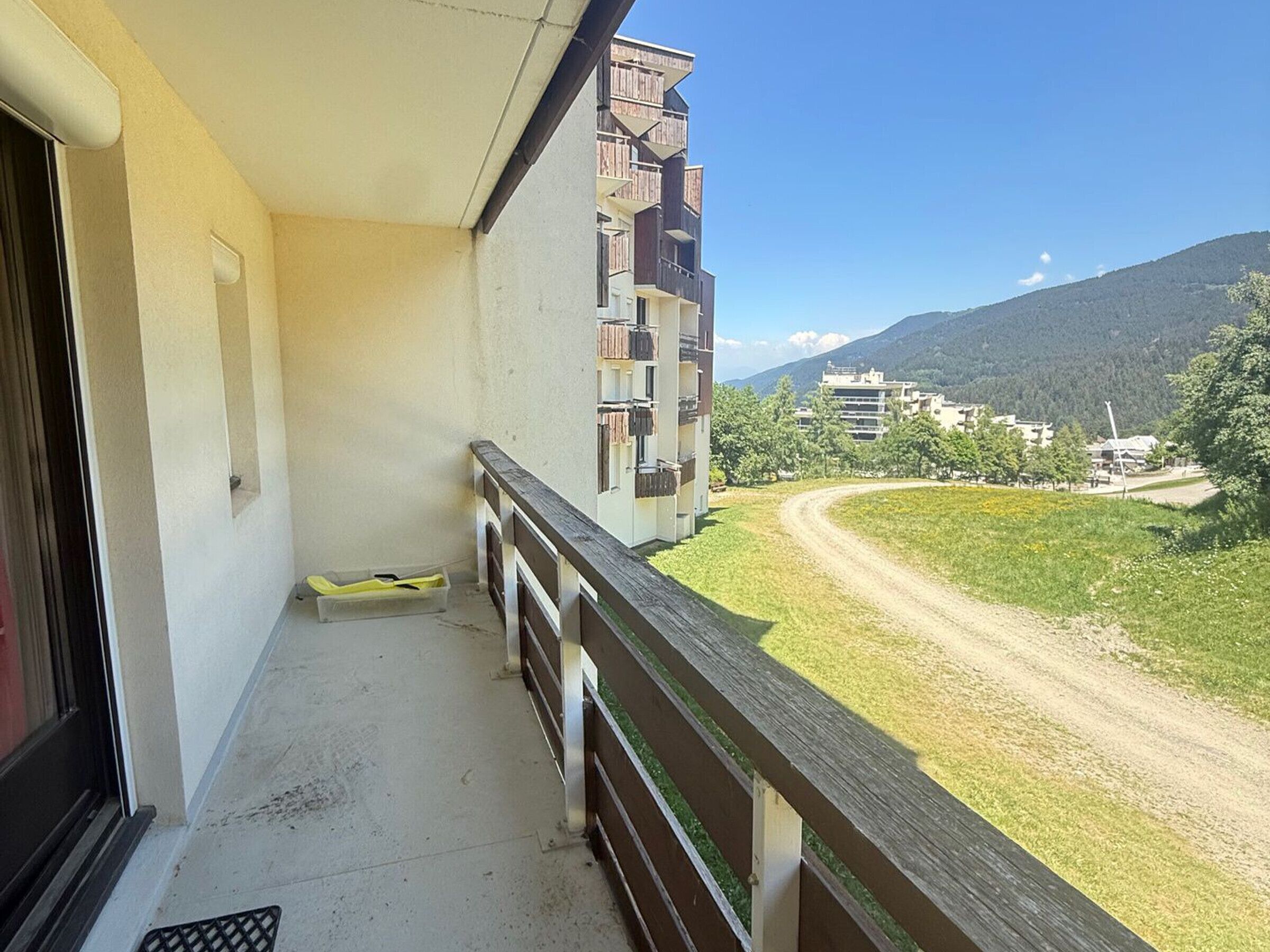 A balcony with a view of a road and buildings in the distance.