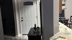 A bathroom with a bathtub, a small table with a decorative item, and a door leading to another room.