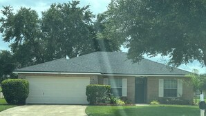 A single-story house with a garage, a driveway, and a well-maintained lawn.