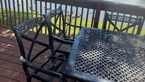 A deck with a table and chairs overlooking a pond with ducks.