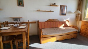 A cozy room with a wooden bed, a dining table with chairs, a lamp, and a window with curtains. - Avoriaz - Apartment 4 people, balcony, wifi (Avoriaz)