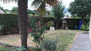A garden with a variety of plants, a palm tree, and a brick structure. - Marjolaine Bed and Breakfast for 2 to 4 guests (Lourdes)