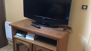 A wooden entertainment center with a flat-screen TV, remote control, and cable box. - Marjolaine Bed and Breakfast for 2 to 4 guests (Lourdes)