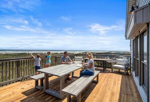 A wooden deck with a table and benches, overlooking a beach and ocean. - Secluded Beachfront House w/ Gorgeous Water Views (Galveston)