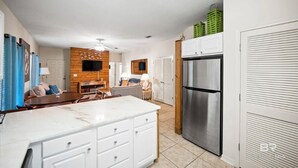 Eine moderne Küche mit weißen Schränken, einem Edelstahl-Kühlschrank und einer Wand mit Holzverkleidung.