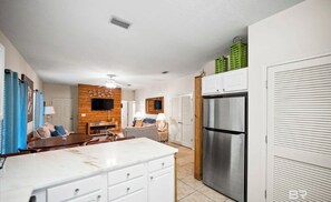 Una cocina moderna con armarios blancos, un refrigerador de acero inoxidable y una pared de acento de madera.