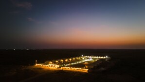 A desert resort with multiple illuminated tents and a central building, surrounded by a well-lit perimeter. - Desert Island Camp & Resort Jaisalmer (Jaisalmer)