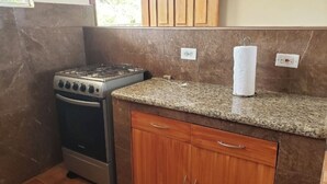 A kitchen with a gas stove, wooden cabinets, and a granite countertop.