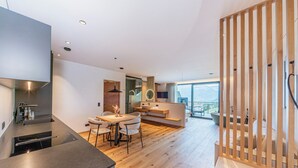 Una cucina moderna con zona pranzo, pavimento in legno e vista sulle montagne attraverso ampie finestre.