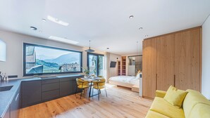 Un ambiente moderno con angolo cottura, zona pranzo e un letto.
