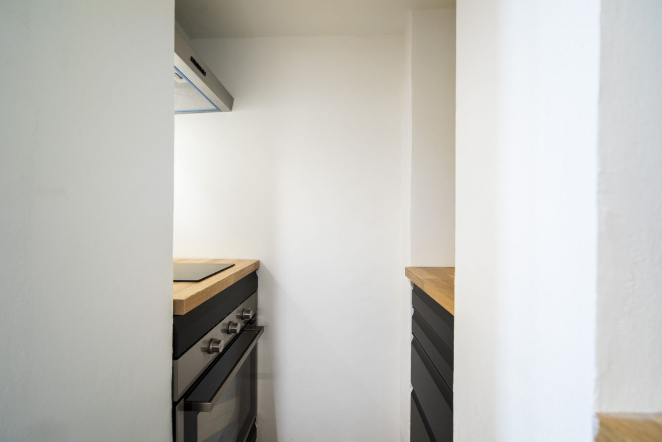 Een kleine keuken met een fornuis, oven en een houten aanrecht.