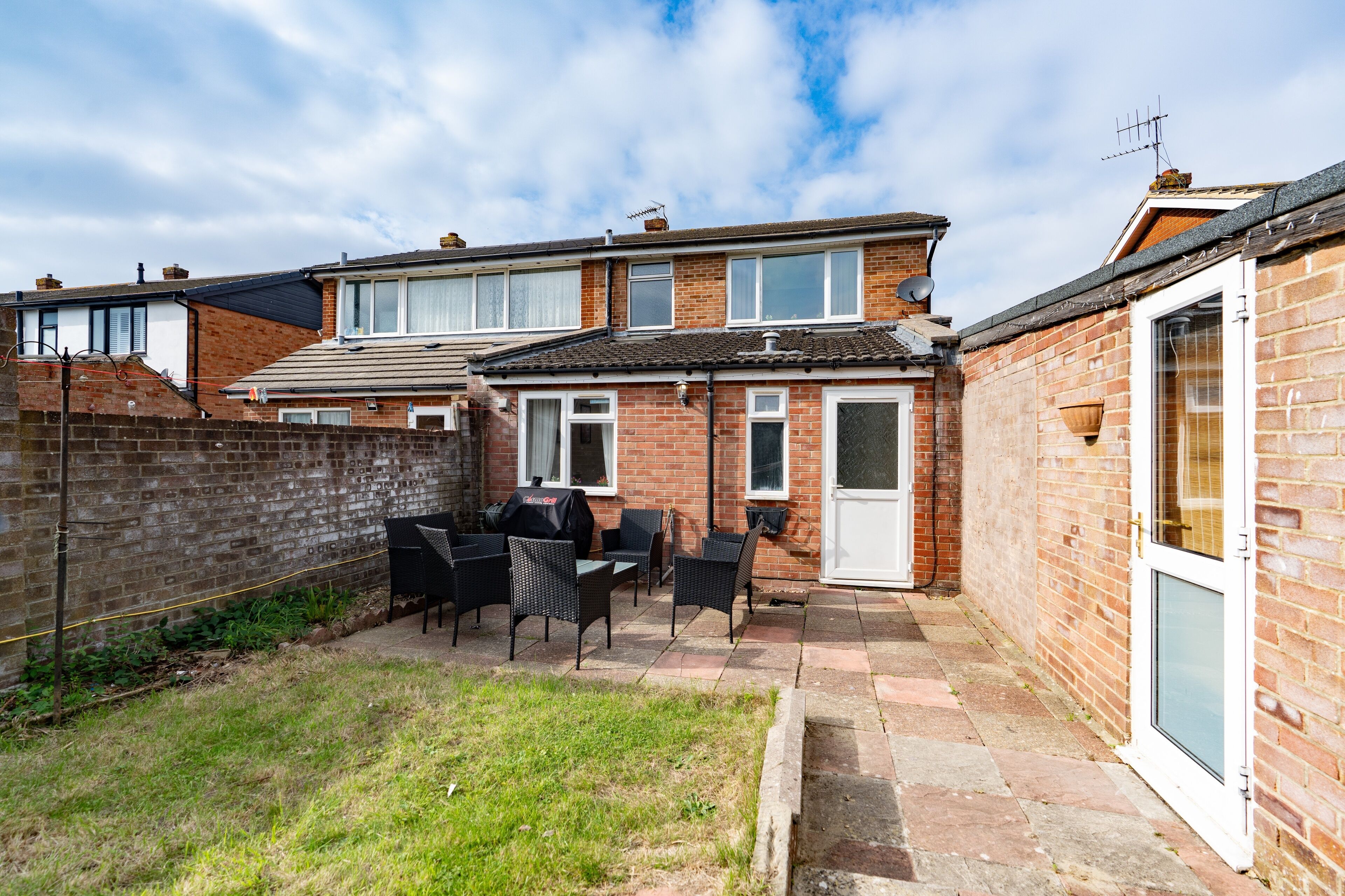 A residential property with a brick exterior, a tiled patio, and outdoor furniture.