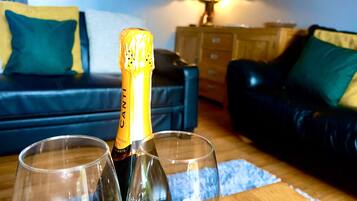 A bottle of Canti champagne and two glasses on a wooden table in a living room.
