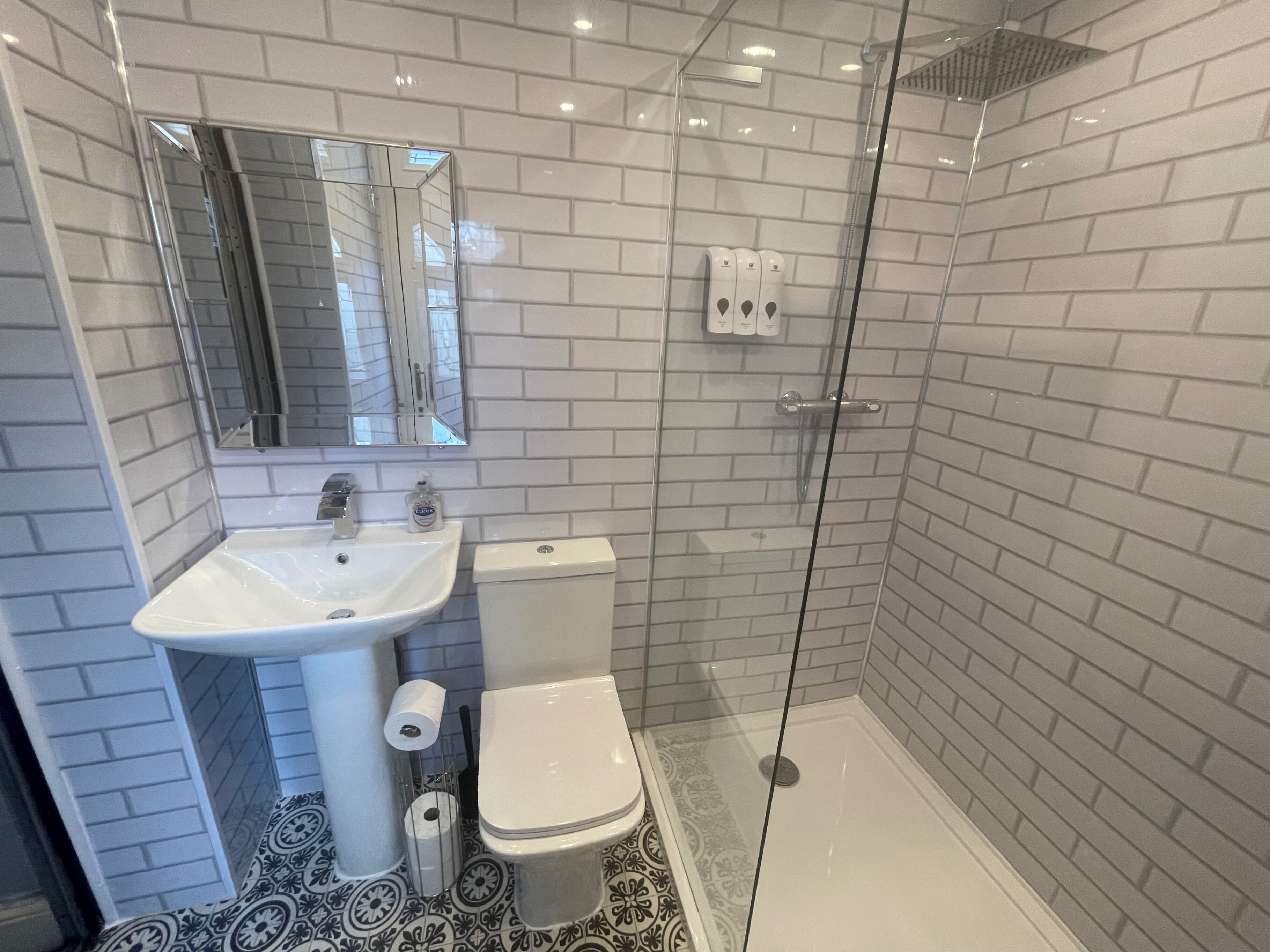 A bathroom with a white sink, toilet, and shower.