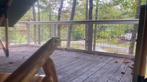 A wooden deck with a railing, overlooking a wooded area. - The Water’s Edge Glamping Tent (Fort Payne)